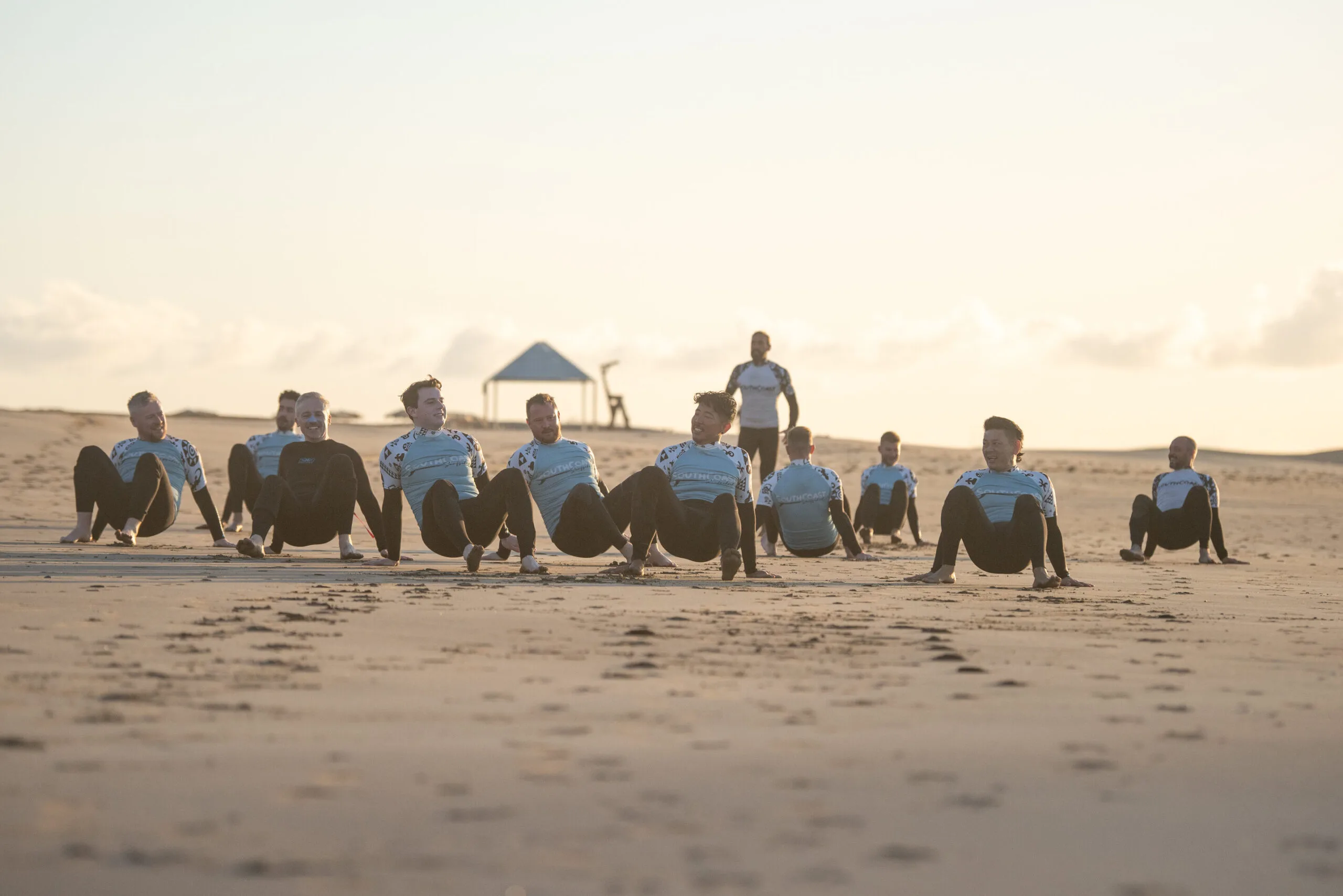Grupo de surferos principiantes calentando en la arena para evitar lesiones