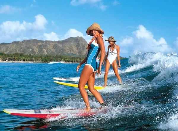 Surfer girls riding a wave